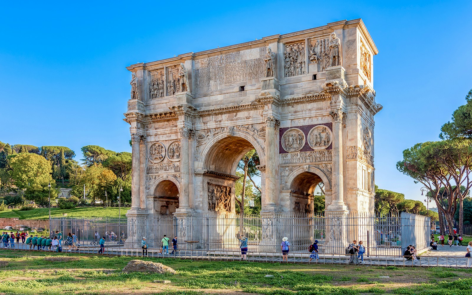 Arch of Constantine in Rome with tourists exploring the historic monument.