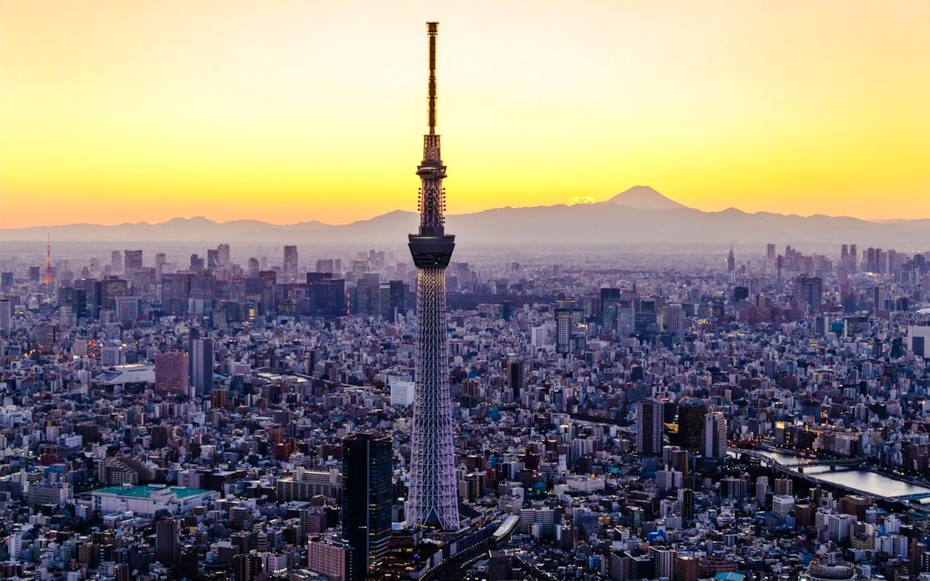 Tokyo Skytree towering over cityscape at sunset.