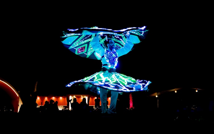 Tanoura dancer performing under lights during desert safari in Abu Dhabi.