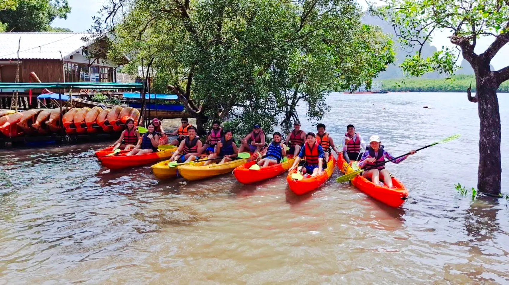 Group kayaking at Ao Thalane, Krabi, with kayaks and mangrove trees in the background.