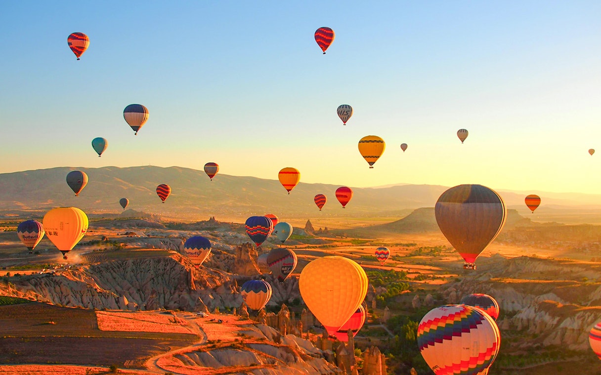 Hot air balloons over Luxor landscape at sunrise.
