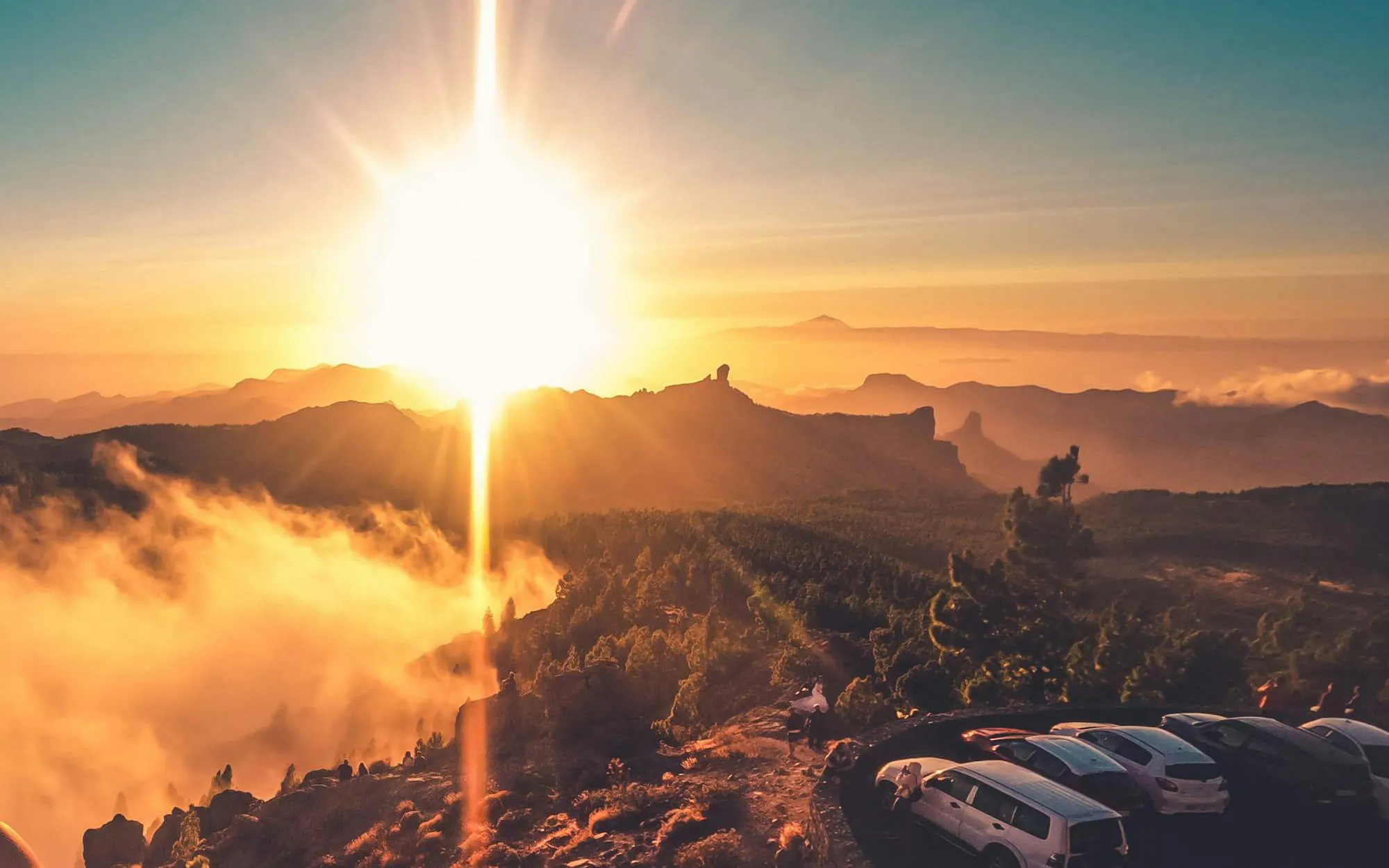 Gran Canaria sunset view over volcanic landscape with parked cars.