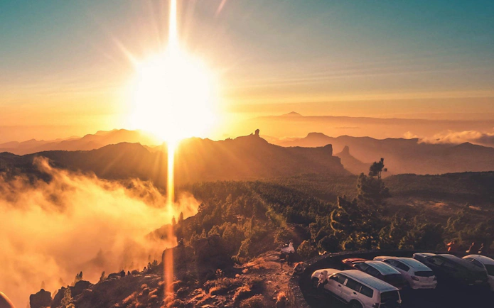 Gran Canaria sunset view over volcanic landscape with parked cars.