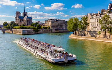 Seine River cruise boat with tourists near Notre-Dame Cathedral, Paris.