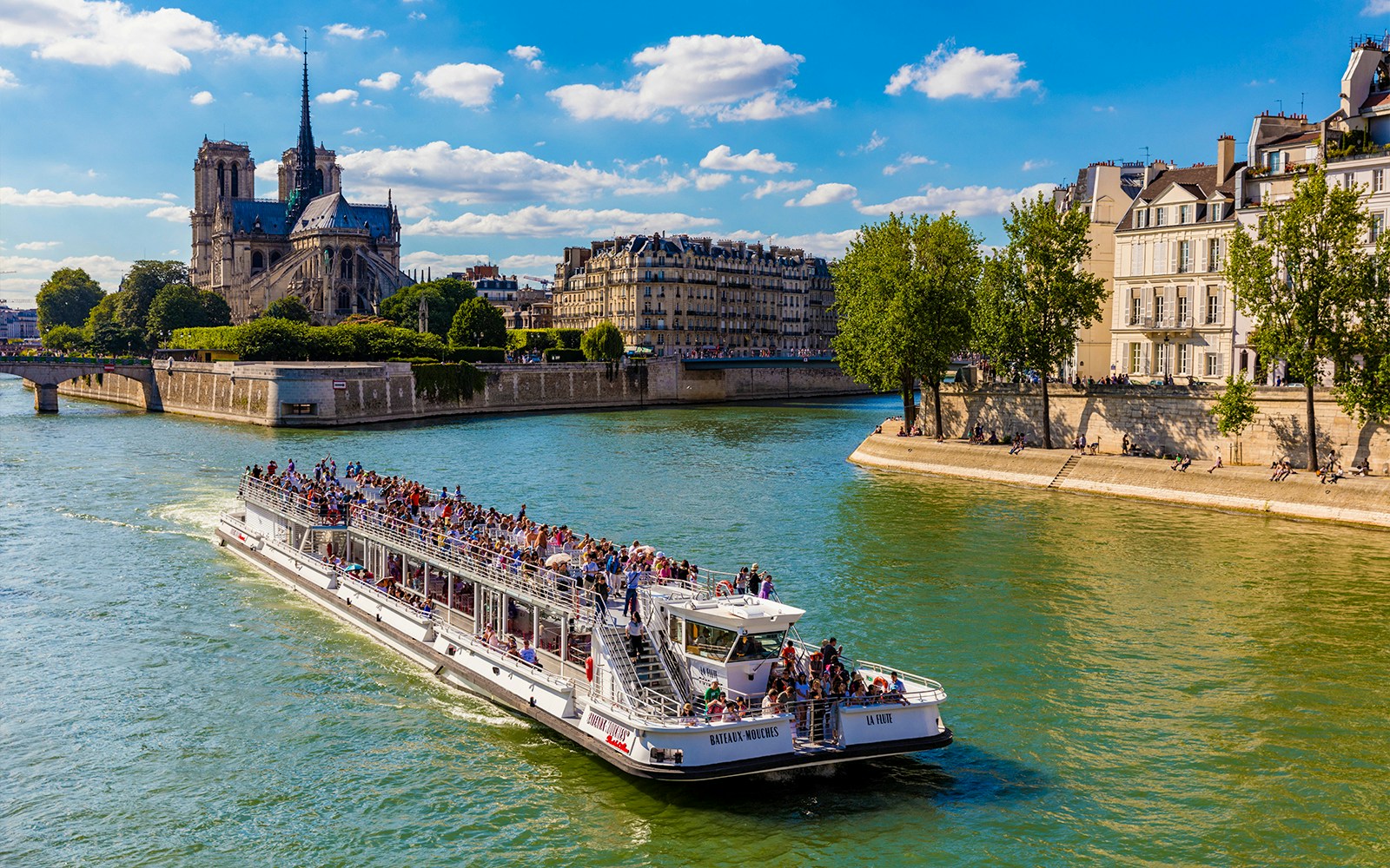 Seine River cruise boat with passengers enjoying live commentary in Paris.