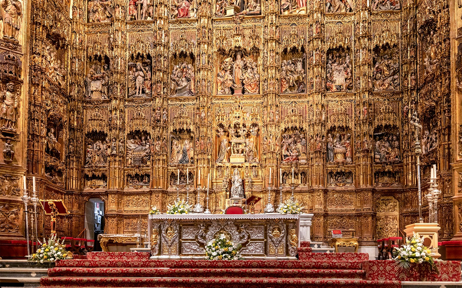 Seville Cathedral's Capilla Mayor with intricate Gothic altar and golden altarpiece.
