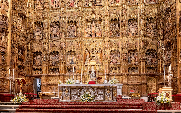 Seville Cathedral's Capilla Mayor altar with intricate gold carvings and religious figures.