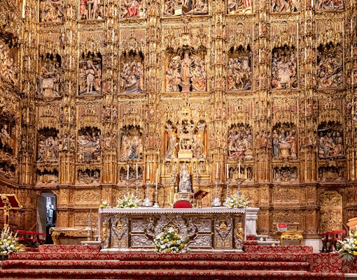 Seville Cathedral's Capilla Mayor with intricate Gothic altar and golden altarpiece.