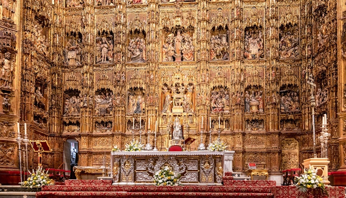 Seville Cathedral's Capilla Mayor with intricate Gothic altar and golden altarpiece.