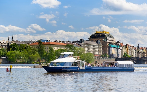Sightseeing cruise on Vltava River with historic Prague buildings in the background.