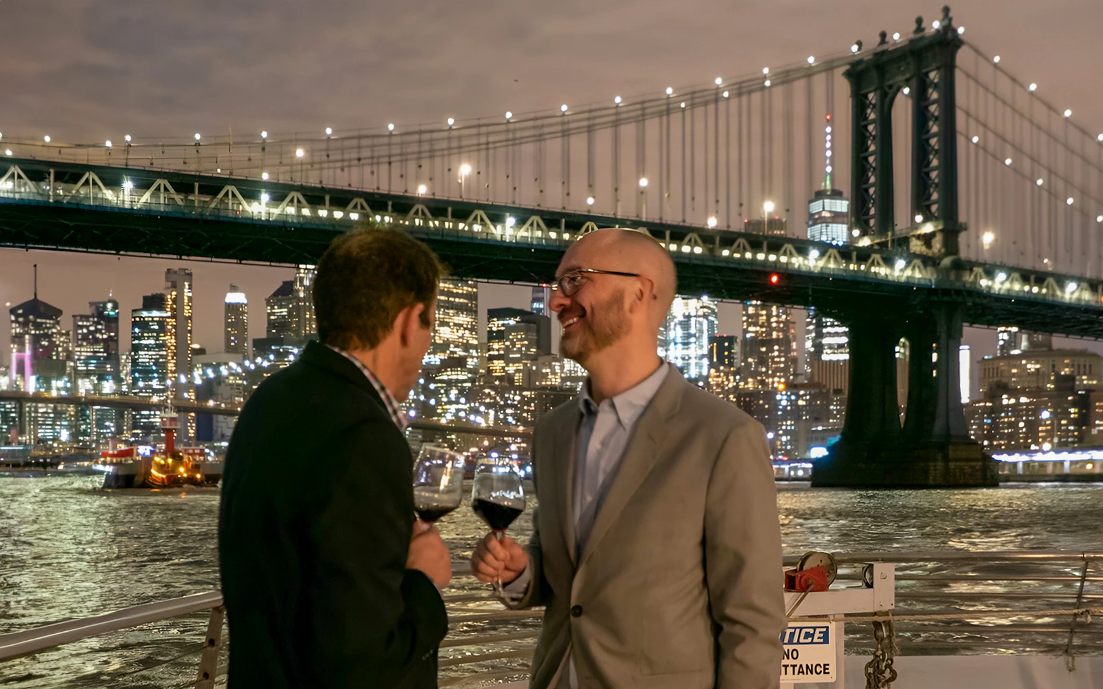 Guests enjoying drinks with New York City skyline in the background on a dinner cruise.