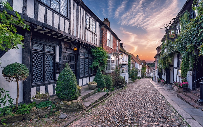 Cobbled street in Windsor lined with historic timber-framed houses at sunset.
