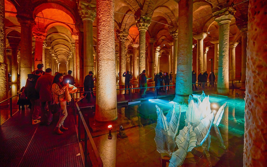 Visitors exploring the illuminated columns of the Basilica Cistern in Istanbul.