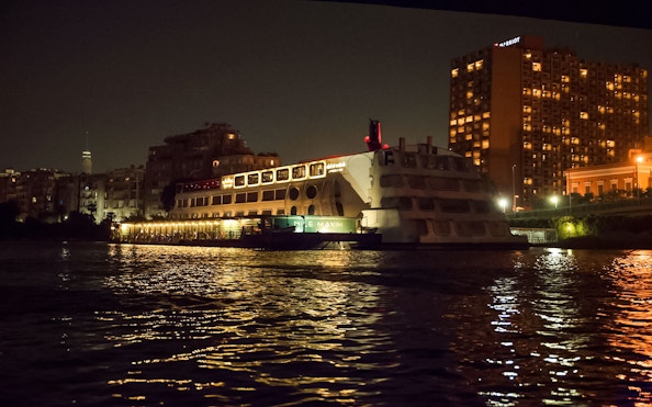 Luxury dinner cruise ship on the Nile River at night, Cairo skyline in background.