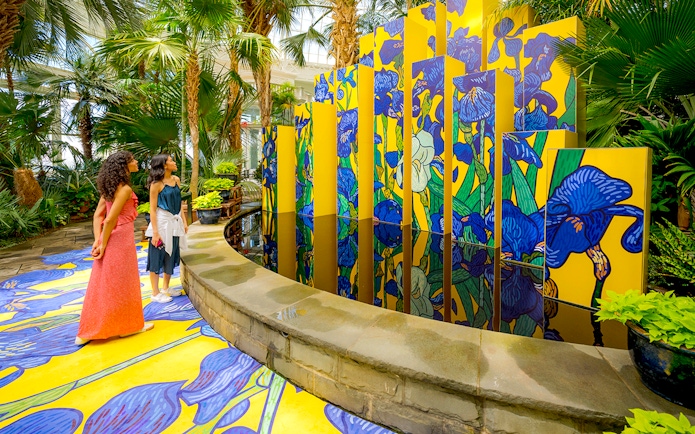 Guests viewing vibrant floral art installation at New York Botanical Garden.