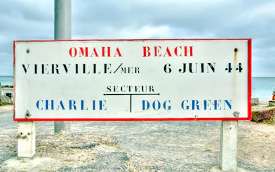 Sign marking Omaha Beach in Vierville-sur-Mer, France, with sector names Charlie and Dog Green.