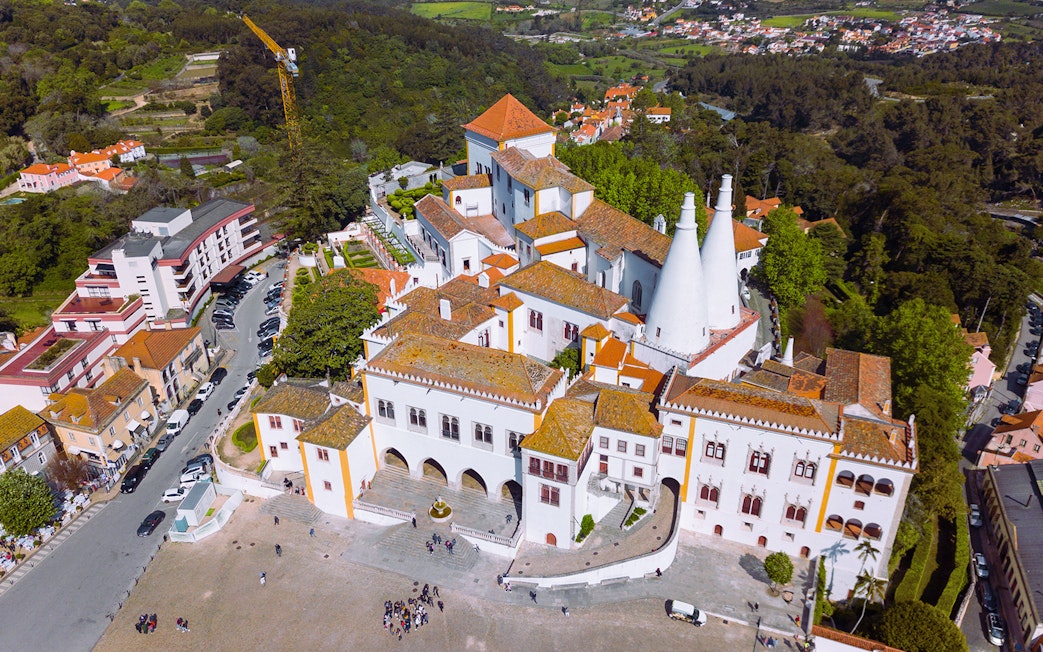 Aerial view of Sintra National Palace with iconic chimneys and surrounding landscape.