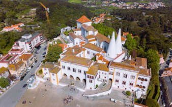 Aerial view of Sintra National Palace with iconic chimneys and surrounding landscape.