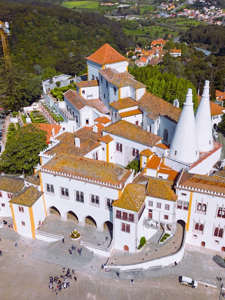 Aerial view of Sintra National Palace with iconic chimneys and surrounding landscape.