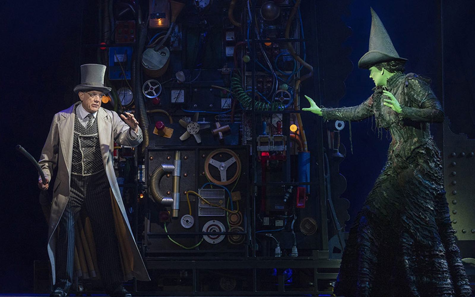 Stage scene from Wicked the Musical with characters interacting in front of machinery.