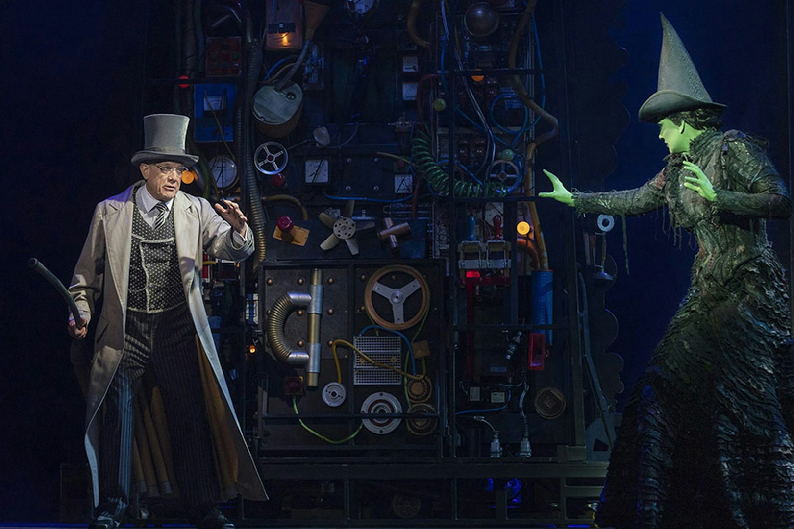 Stage scene from Wicked the Musical with characters interacting in front of machinery.