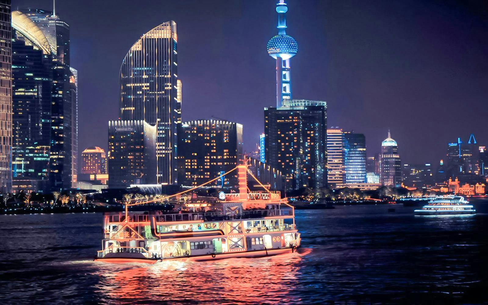 Cruise boat on Huangpu River with Shanghai skyline and Oriental Pearl Tower.