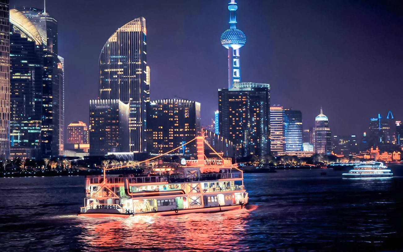 Cruise boat on Huangpu River with Shanghai skyline and Oriental Pearl Tower.