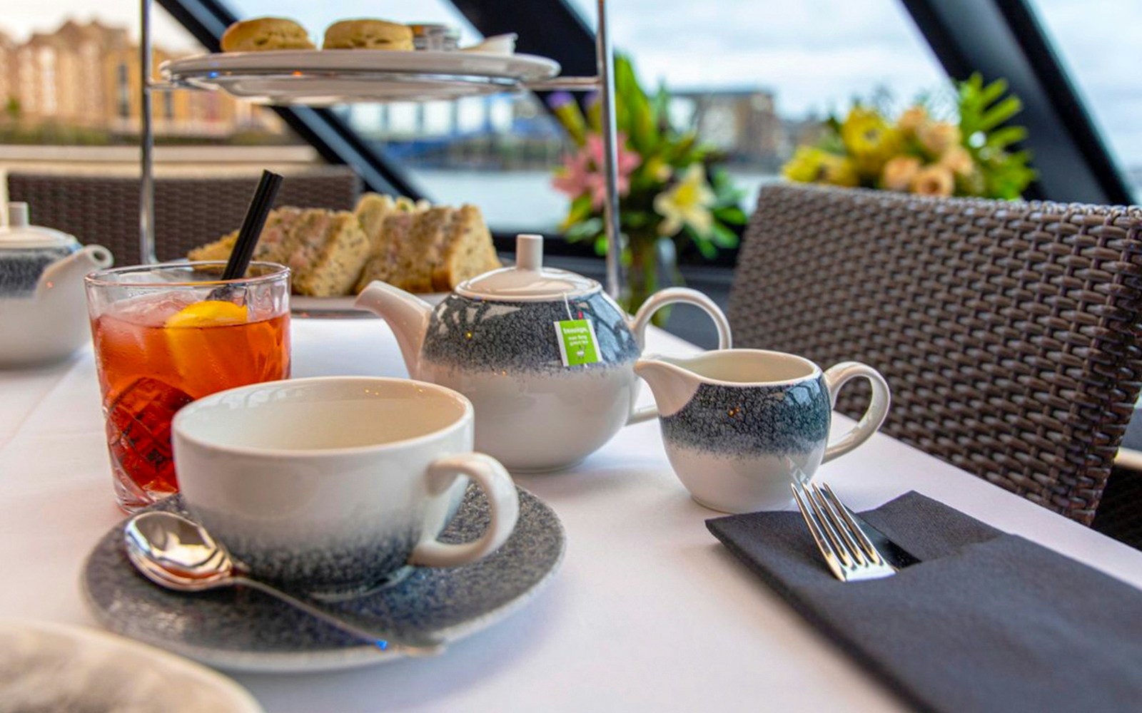 Guests enjoying tea and scones on a Thames River Cruise with views of London landmarks.