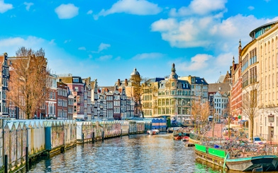 Amsterdam canal with historic buildings and houseboats in early spring.