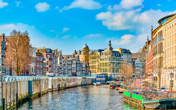 Amsterdam canal with historic buildings and houseboats in early spring.