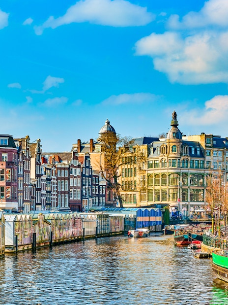 Amsterdam canal with historic buildings and houseboats in early spring.