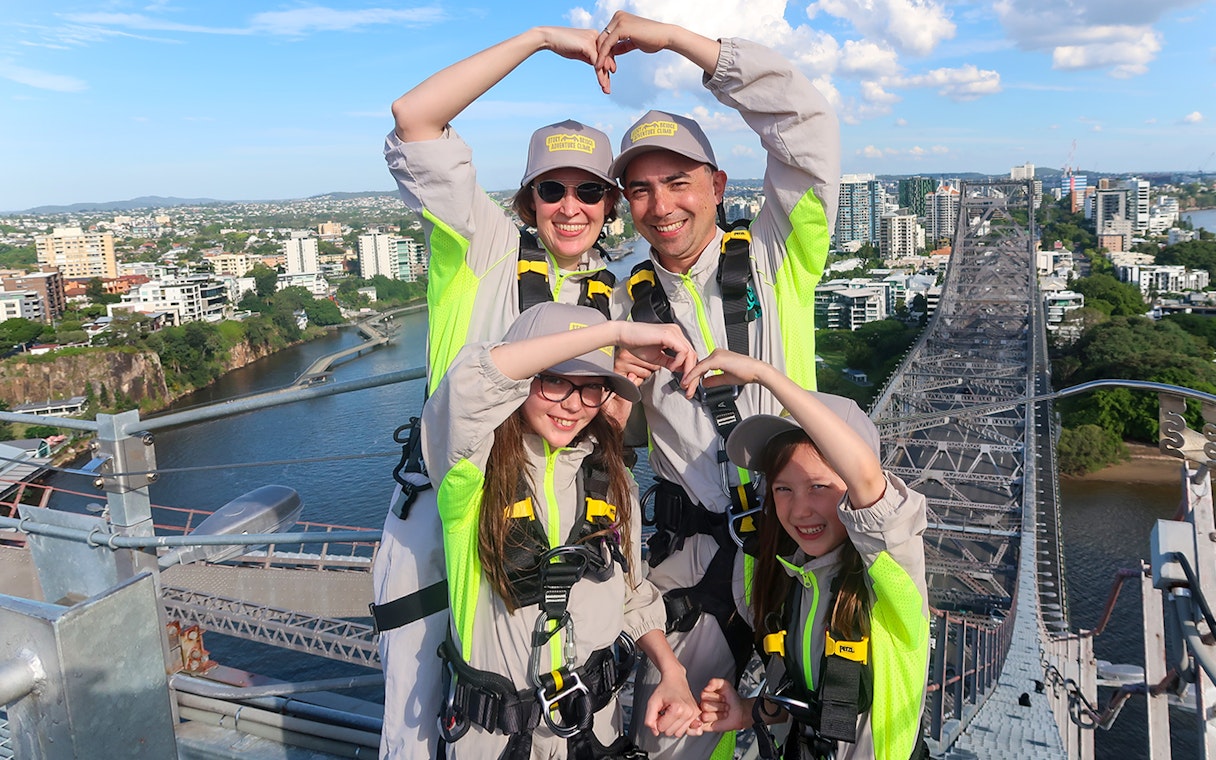 Family making heart shape with arms atop Story Bridge, Brisbane.