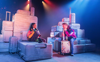 Actors surrounded by luggage in a scene from Two Strangers (Carry a Cake Across New York) Broadway show.