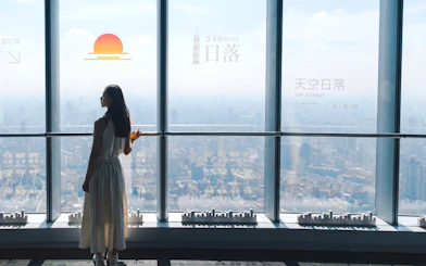 Person viewing Shanghai skyline from Shanghai Tower observation deck at 546 meters.