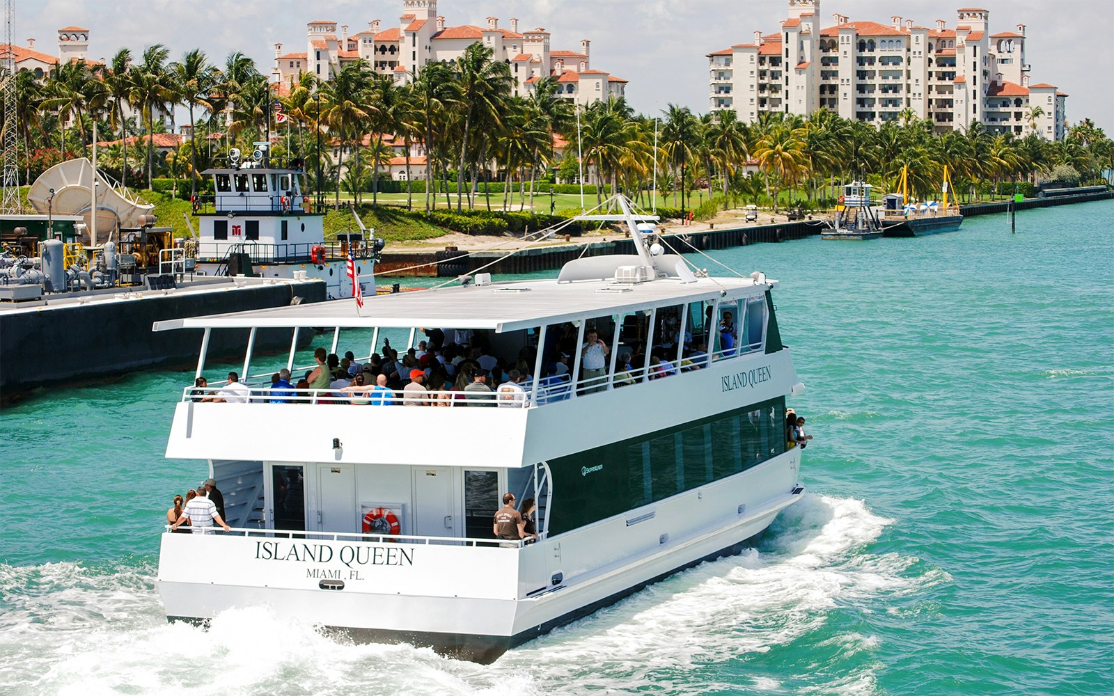 Tourists on "Island Queen" ferry enjoying Miami skyline views.