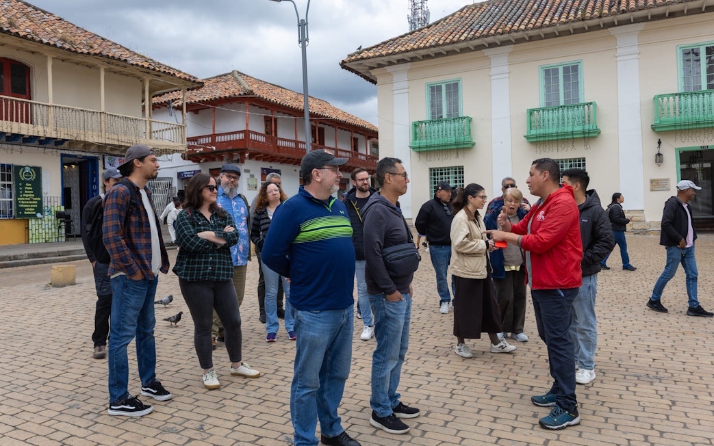 Tour guide briefing tourists about Zipaquira Salt Cathedral tour in a plaza.