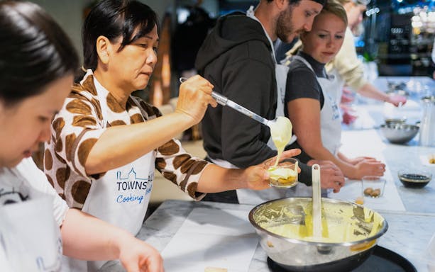 Participants preparing tiramisu during a cooking class in Milan.