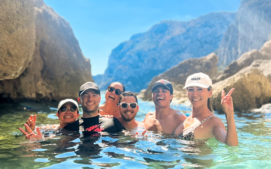 Group enjoying a kayak tour in Capri, surrounded by rocky cliffs and clear water.