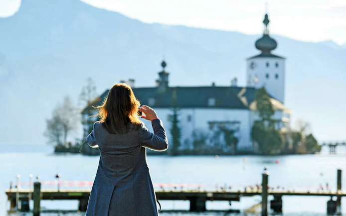 Person photographing Schloss Ort on Lake Traunsee, Hallstatt, Austria.