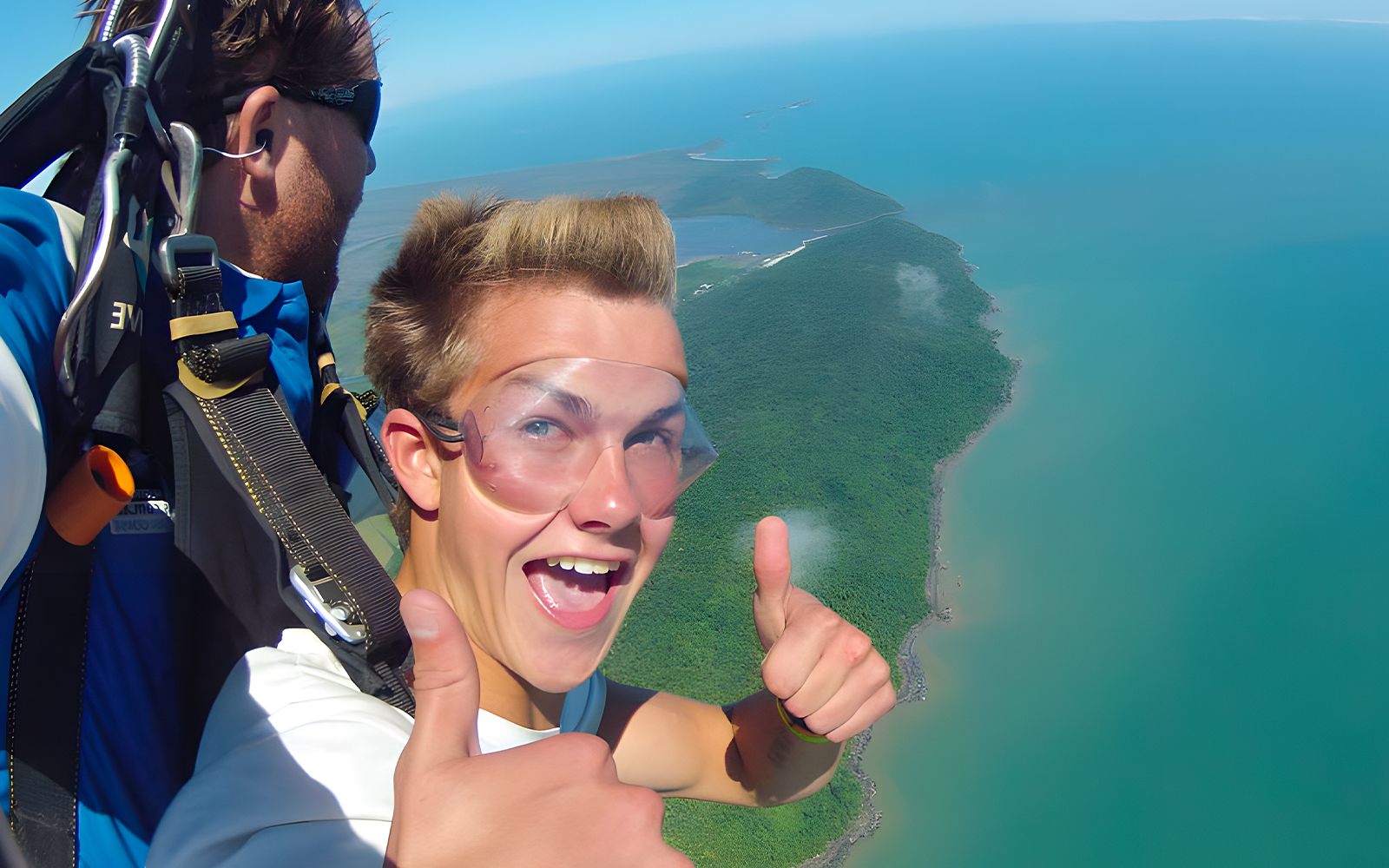 Tandem skydive over Cairns coastline with ocean and forest views.