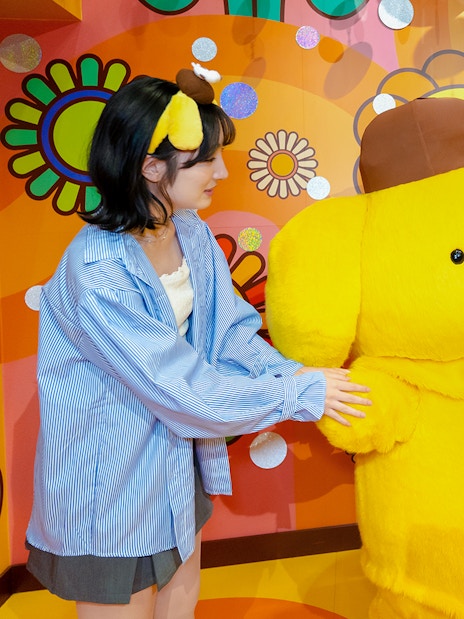 Visitors interacting with a large yellow character at Sanrio Puroland.