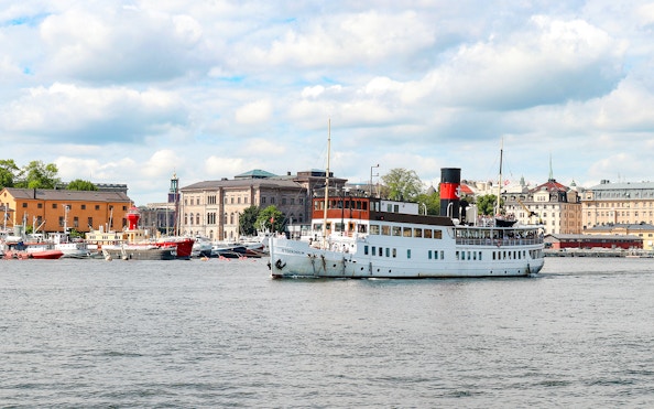 Cruise ship sailing near Stockholm waterfront with historic buildings in view.