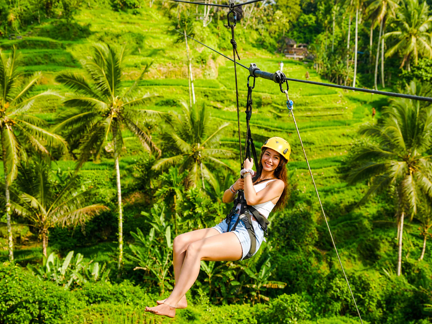 Person ziplining over lush rice terraces in Ubud, Bali.