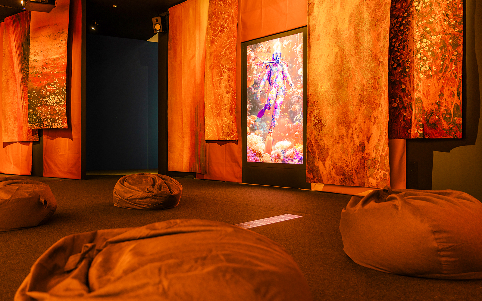 Display screen with person in colorful outfit in abstract underwater scene, surrounded by vibrant decor.