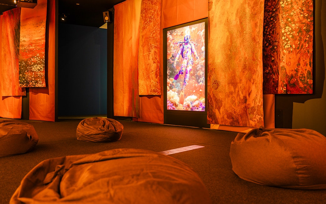 Display screen with person in colorful outfit in abstract underwater scene, surrounded by vibrant decor.