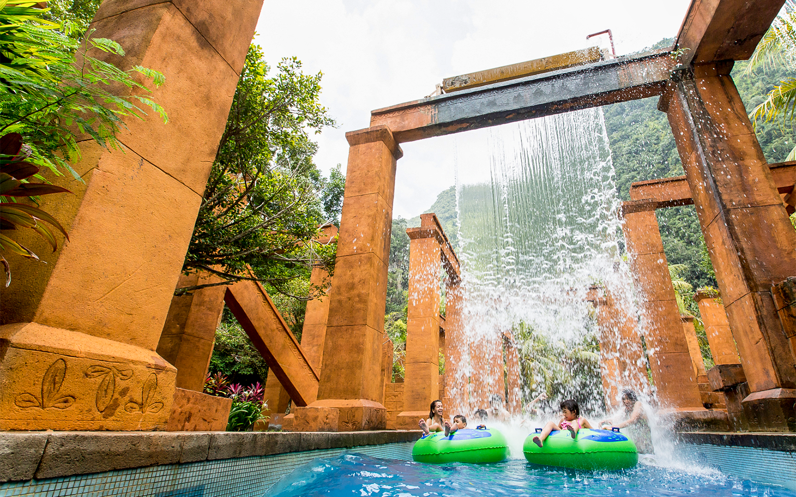 Visitors on water tubes under waterfall at Sunway Lost World of Tambun, Malaysia.