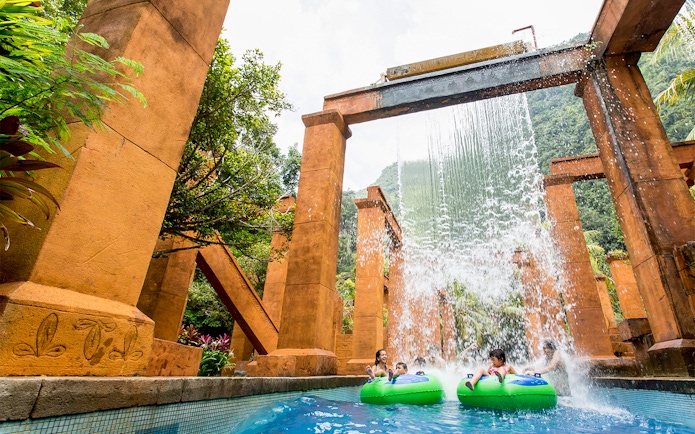 Visitors on water tubes under waterfall at Sunway Lost World of Tambun, Malaysia.