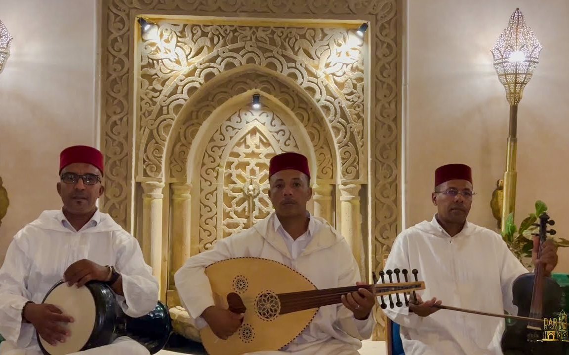 Musicians in traditional Moroccan attire playing instruments in a decorated setting.