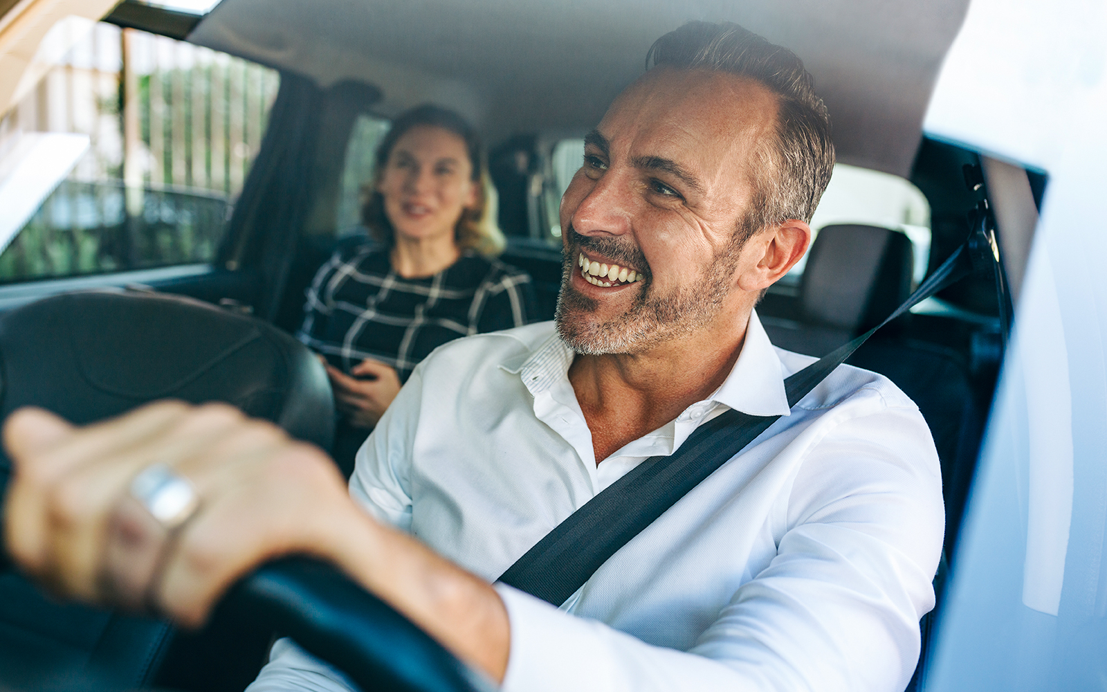 Smiling taxi driver with passenger in the back seat.