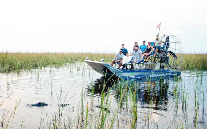 Airboat with tourists exploring Everglades wetlands during a night tour.
